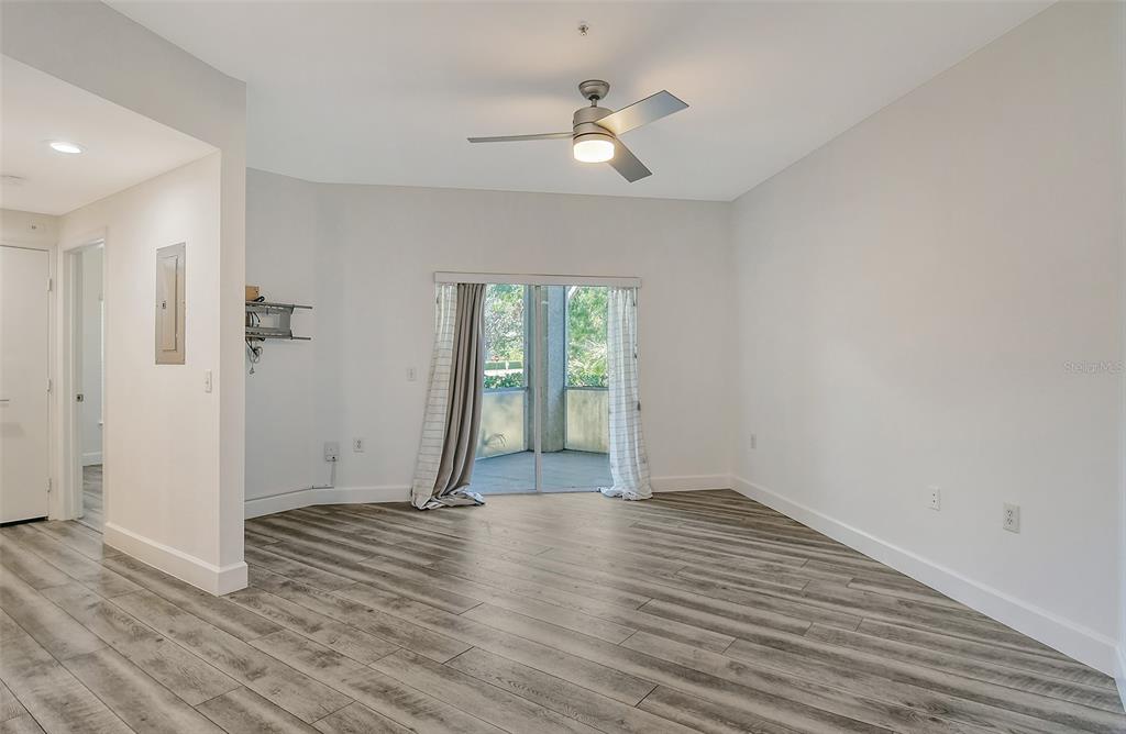A living room with light gray walls, wood-look flooring, a ceiling fan, and sliding glass doors — 5160 NORTHRIDGE ROAD UNIT 107, SARASOTA, FL