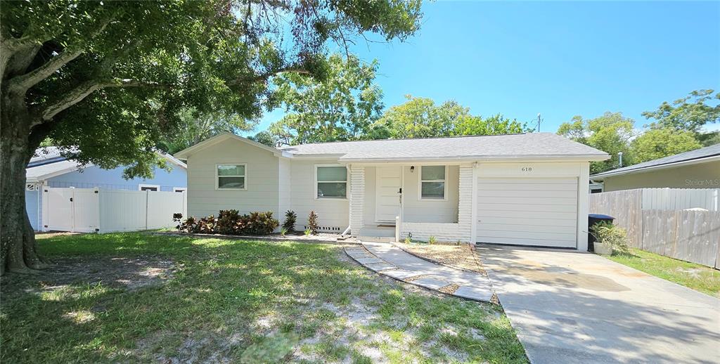 A single-story house with a white exterior, a front garage, and a paved walkway — 618 S CREST AVE, CLEARWATER, FL