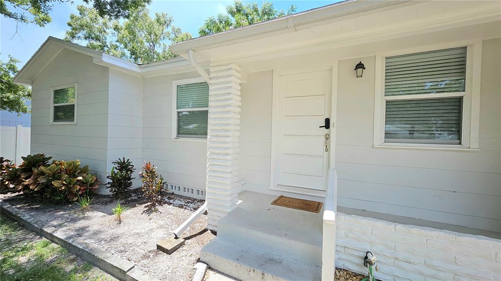 A white house exterior features a front door, a small concrete porch, and landscaping — 618 S CREST AVE, CLEARWATER, FL