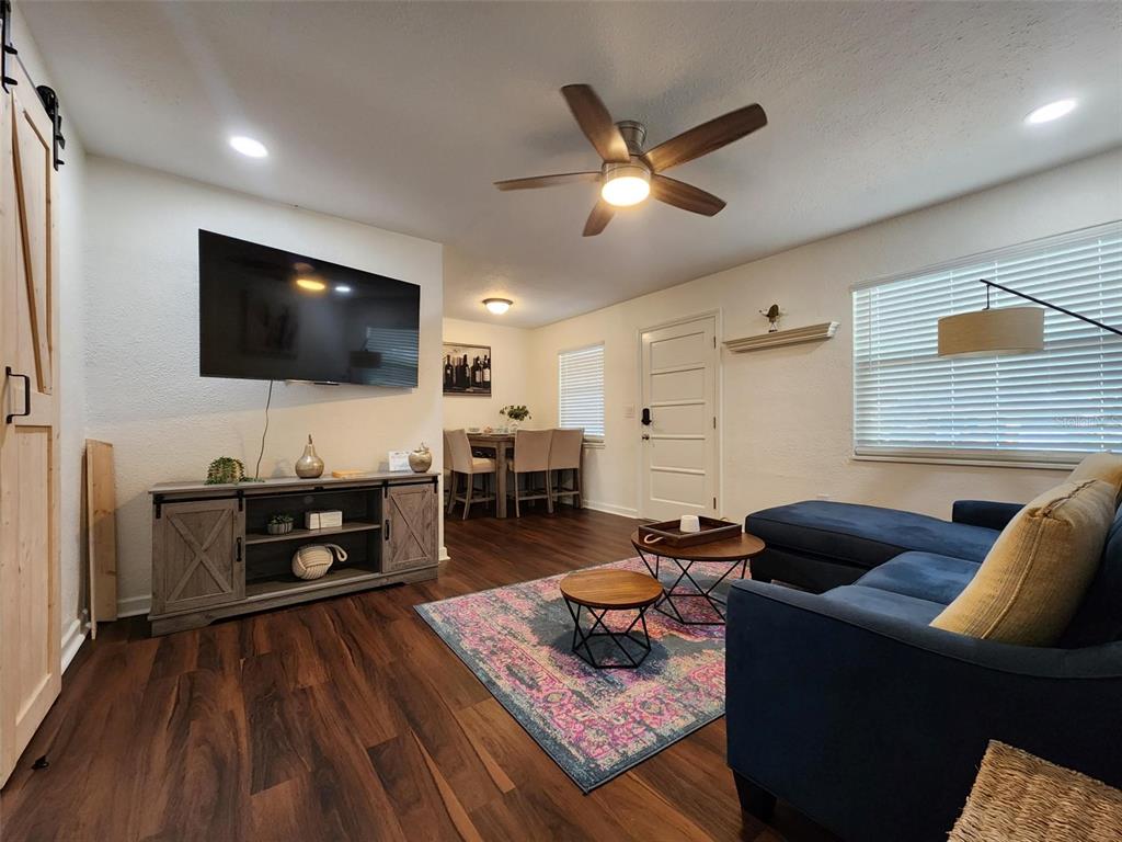A living room features dark wood floors, a blue sectional sofa, and a wall-mounted television — 618 S CREST AVE, CLEARWATER, FL