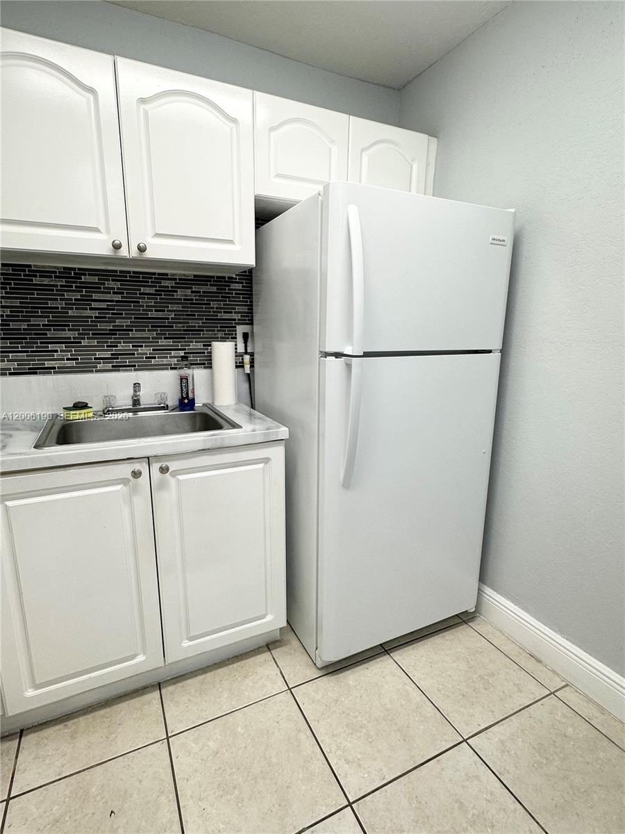 A small kitchen features white cabinets, a stainless steel sink, and a white refrigerator — 9405 SW 76th St # Y32, Miami FL 33173, MIAMI, FL