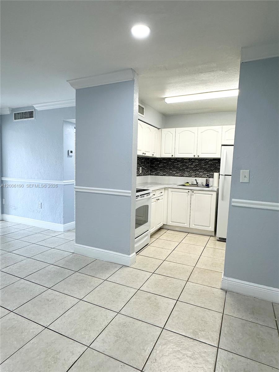 A kitchen with white cabinets, tiled floors, and a dark backsplash is visible — 9405 SW 76th St # Y32, Miami FL 33173, MIAMI, FL