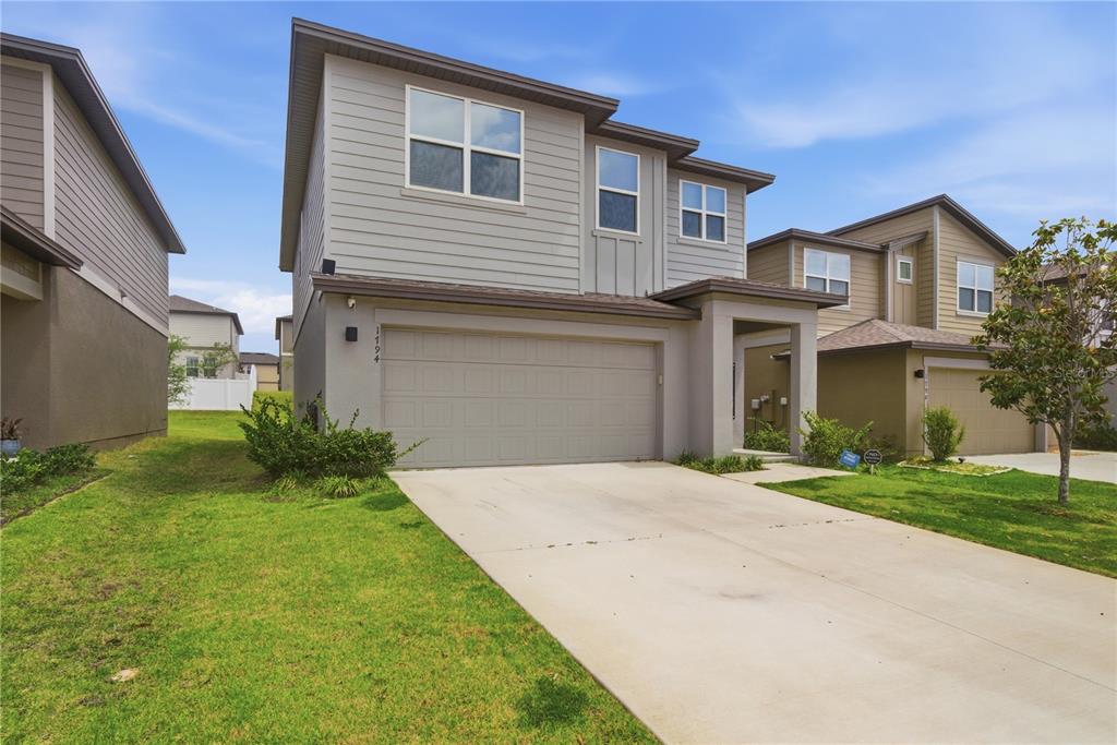 A two-story suburban house with gray siding, a two-car garage, and a concrete driveway — 1794 SUNDANCE CHASE ROAD, MINNEOLA, FL