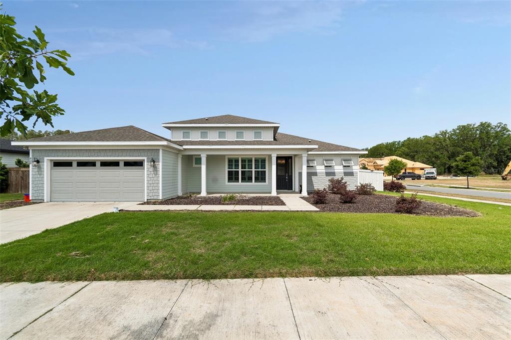A single-story house with light green siding, a two-car garage, and a front porch — 428 SW 144TH DRIVE, NEWBERRY, FL