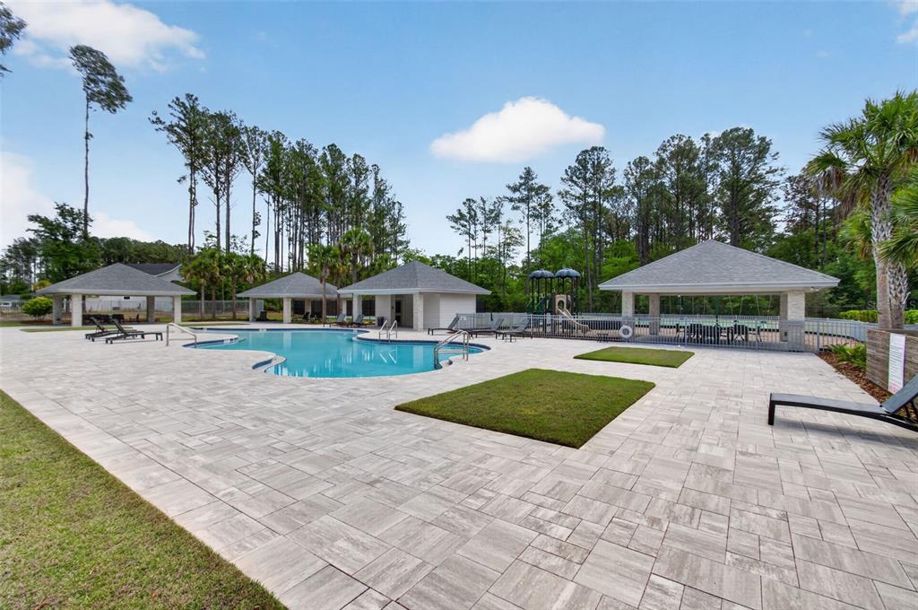 An outdoor swimming pool area features a paved deck, multiple gazebos, and a small playground — 428 SW 144TH DRIVE, NEWBERRY, FL