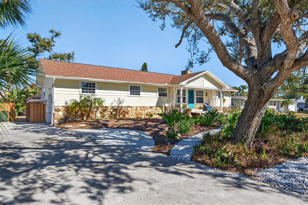 A single-story house with light yellow siding, a stone base, and a concrete driveway — 504 BAYVIEW PARKWAY, NOKOMIS, FL