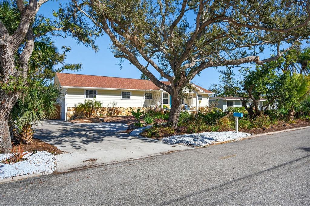 A single-story house with light siding, a stone base, and a large tree in front — 504 BAYVIEW PARKWAY, NOKOMIS, FL