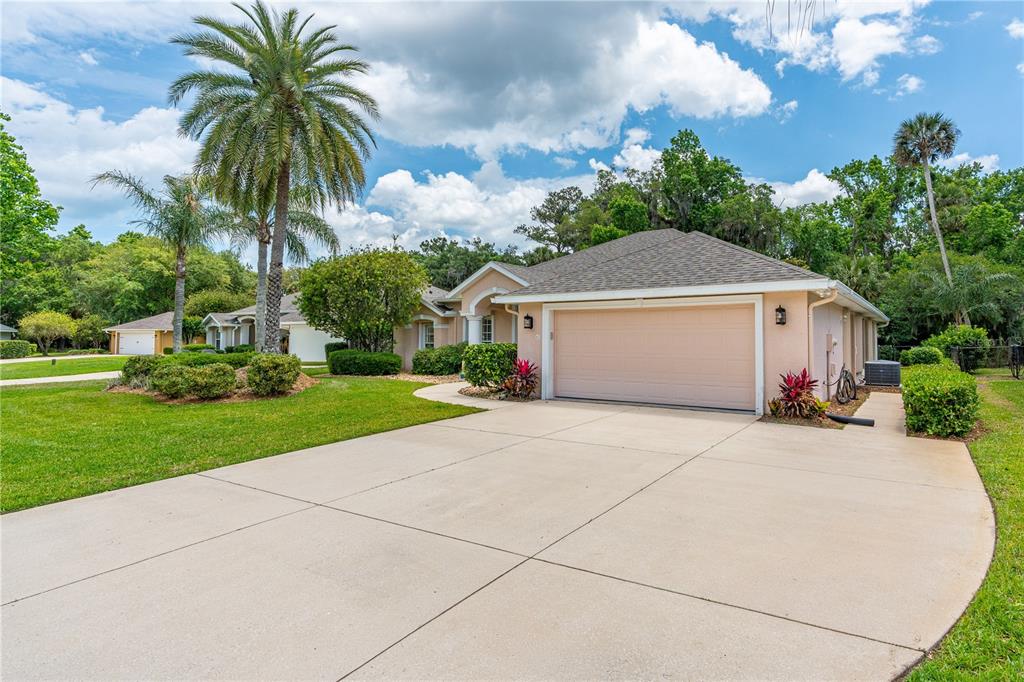 A single-story house with a two-car garage, a concrete driveway, and palm trees — 12 JOLYNN DRIVE, ORMOND BEACH, FL