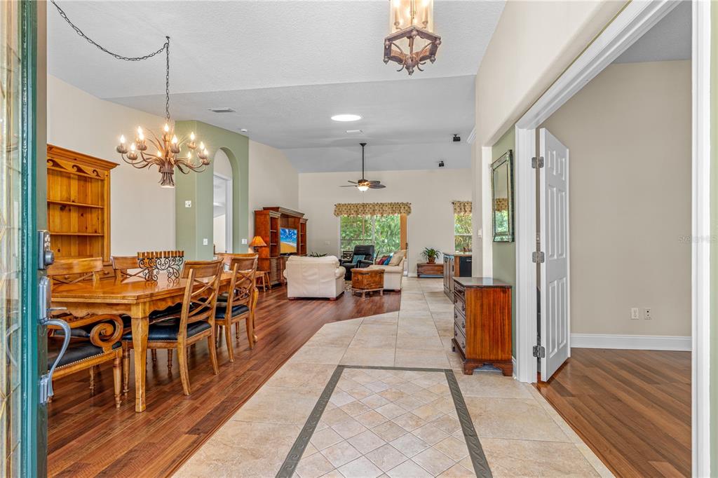 An open-concept living and dining area features wood flooring, tile entry, and vaulted ceilings — 12 JOLYNN DRIVE, ORMOND BEACH, FL