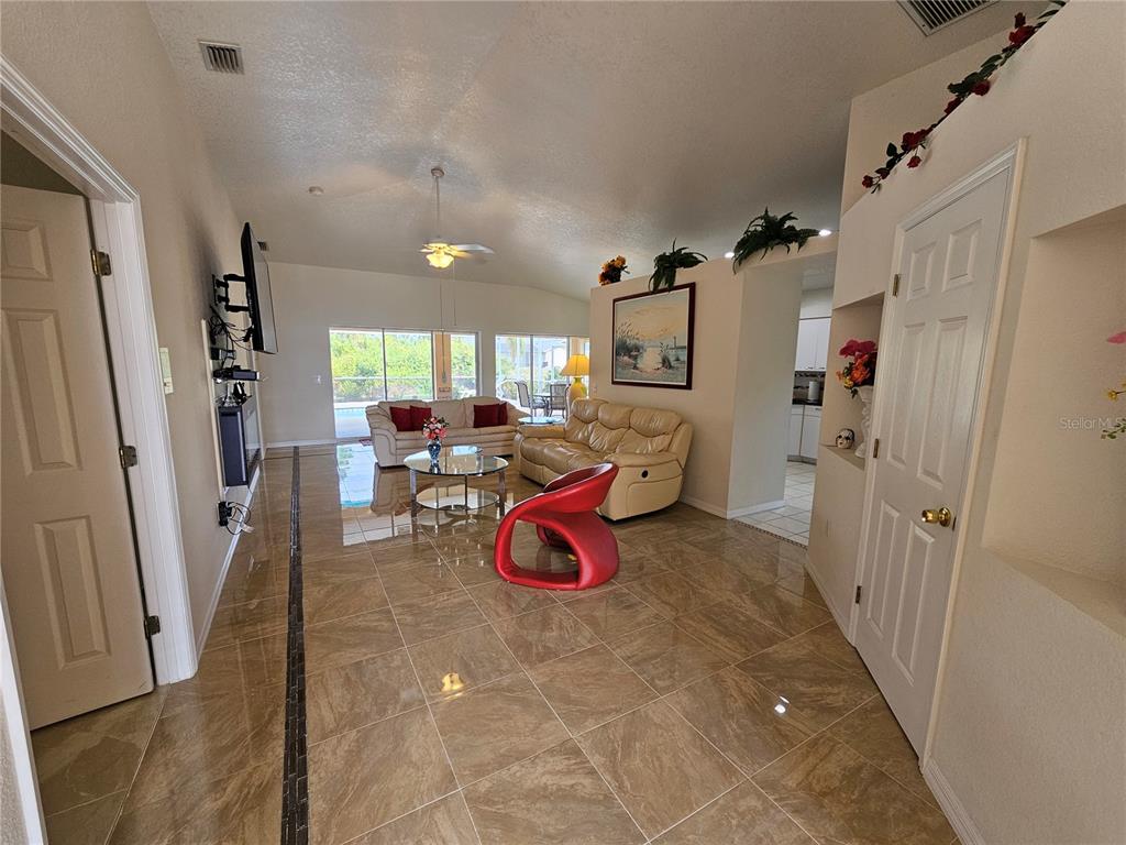 A living room with beige tile floors, a red chair, and two sofas — 114 ALBATROSS ROAD, ROTONDA WEST, FL