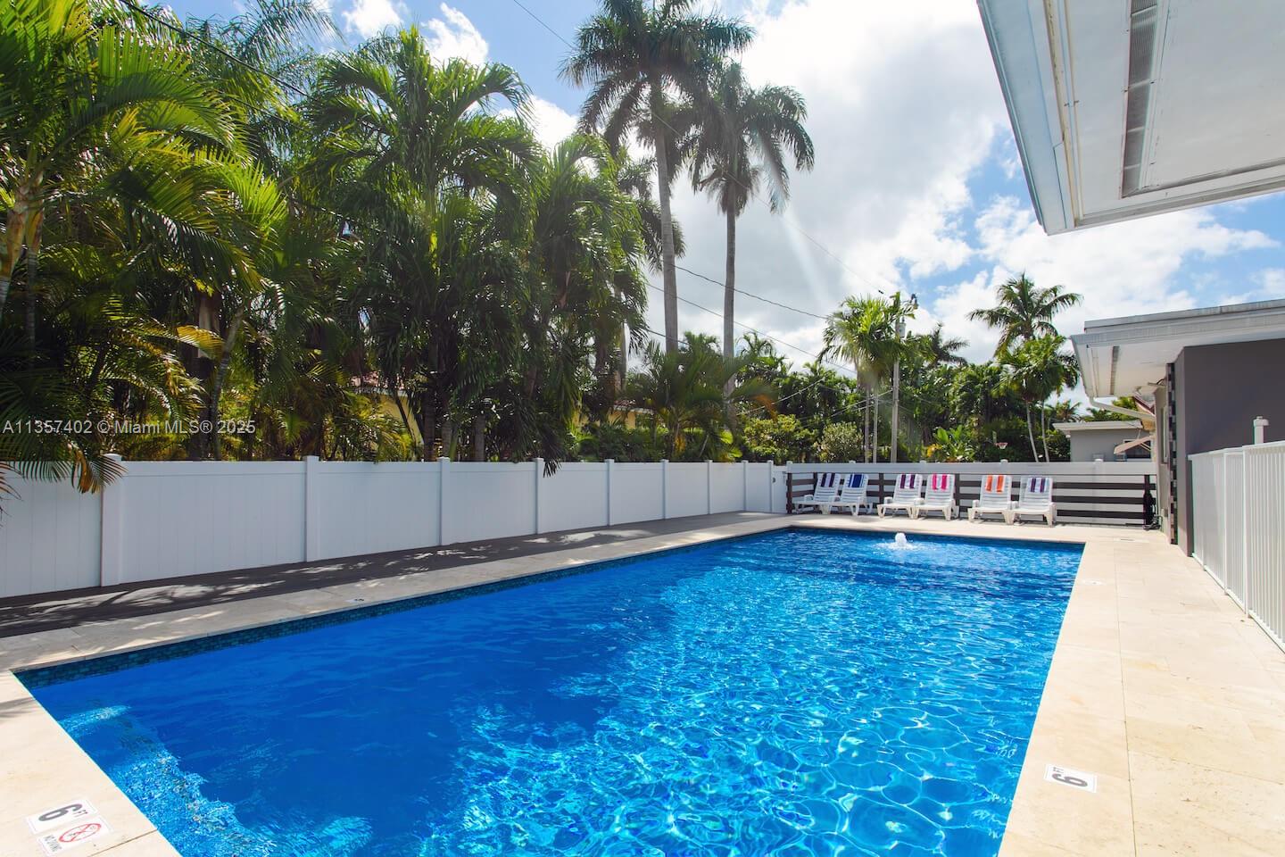 A rectangular swimming pool with a white fence and palm trees in the background — 1218 Hollywood Blvd, Hollywood FL 33019, HOLLYWOOD, FL