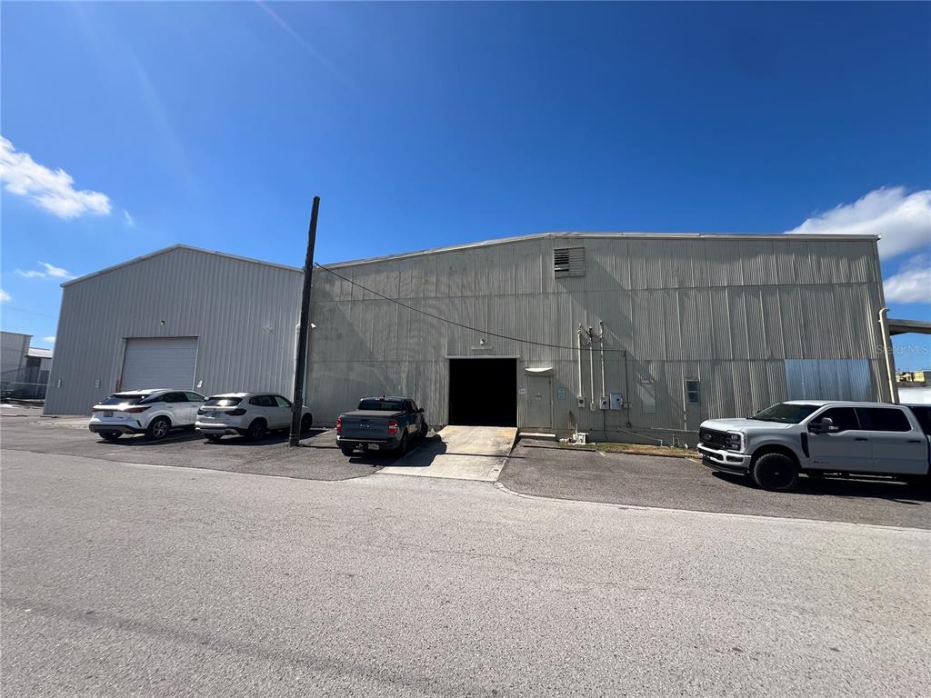 The exterior of a metal industrial warehouse building features a loading dock and parking area — 5705 E HANNA AVENUE, TAMPA, FL