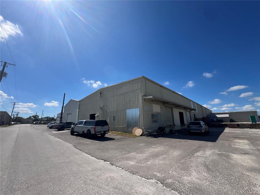 An exterior view of a large, beige industrial warehouse building with a paved parking lot — 5705 E HANNA AVENUE, TAMPA, FL