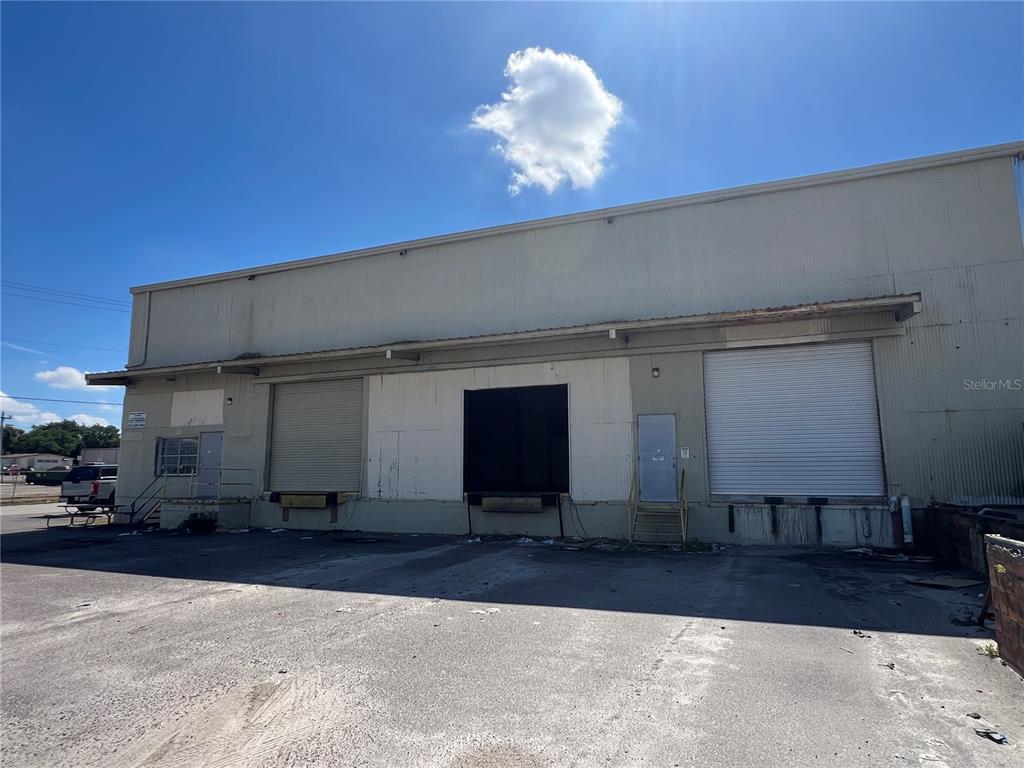 A warehouse exterior features three loading dock bays and two metal entry doors under a canopy — 5705 E HANNA AVENUE, TAMPA, FL