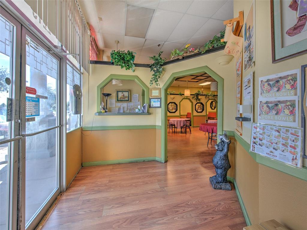 An interior view of a restaurant entrance featuring wood-look flooring, green trim, and dining tables — 2215 COLLIER PARKWAY, LAND O LAKES, FL